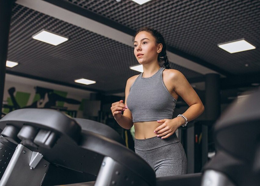 Девушка бегает на беговой дорожке